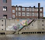 1466_3980 Im Billhafen fhrt eine Treppe hinunter zum Wasser des Hafenbeckens - die Wand ist mit buntem Graffiti bedeckt. Hinter der Kaimauer die dunkelroten Klinker eines der historische Gebude am Billehafen.