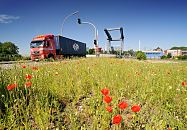 185_0871 Ein Containerlastzug hat die Reiherstiegklappbrcke berquert; die Brcke ber den Reiherstieg wurde 1982 erbaut und ist die grsste Waagebalkenklappbrcke ihrer Art in Europa. Im Vordergrund blht der rote Klatschmohne auf dem Brachland.
