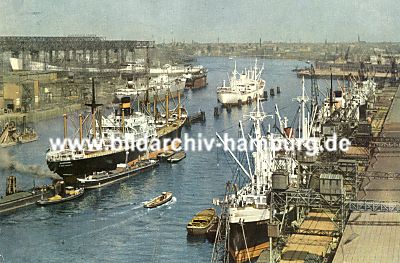 011_15871 - Frachter liegen im Hamburger Hafen am Kai und auf Reede - sie werden mit Kranen entladen; Schuten bernehmen den Weitertransport  ( historisches Motiv ca. 1956).