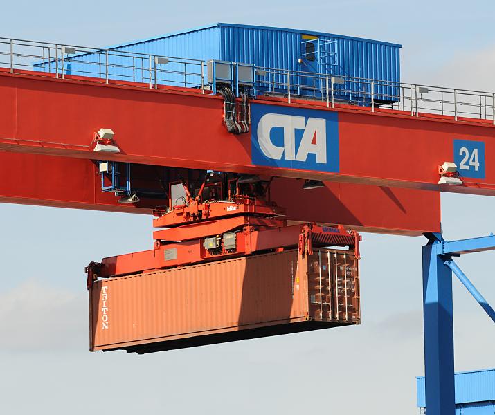 Fotos  aus dem Container-Hafen Hamburg;  FEU-Container Portalkrananlage Containerkran  transportiert einen Container / Schriftzug CTA.  89_6934 Ein Container hngt im Spraeder eines der Portalkrne auf dem Lagergelnde des Terminals Altenwerder. Der Spreader (Containergeschirr) hat Teleskoprahmen, die auf die unterschiedlichen Lngen (20', 30', 40' oder 45') der Containers eingestellt werden kann und so in die vier oberen Eckbeschlge des Containers eingreifen und sich dort durch Drehen mit den Twistlocks verriegeln.