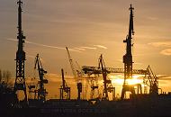 07_26041 Im Hamburger Hafen geht die Sonne unter. Die Silhouetten der Hafenkrne der Werft Blohm + Voss zeichnen sich im roten Abendhimmel ab. 