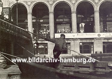 011_15636 - auf der Fotografie von ca. 1925 stakt ein Schiffer mit einer langen Stange sein Schiff zum Anleger; ganz lks. sind Scke gestapelt - in den Alsterarkaden die Aufschriften der unterschiedlichen Geschfte. 