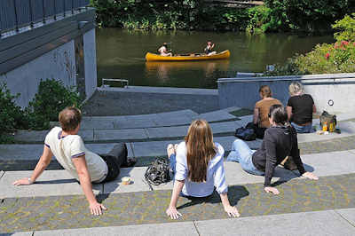 1818 Winterhuder sitzen in der Sonne am Goldbekkanal Hhe Goldbekplatz - ein Kanu fhrt vorber.