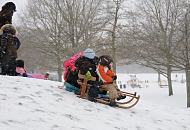 276_5027 Im dichten Schneetreiben lassen sich die Kinder ihren Spass nicht nehmen, einen kleinen Hgel im Hamburger Stadtpark herunter zu rodeln. Im Hintergrund der Spielplatz und das eingeschneite Planschbecken.