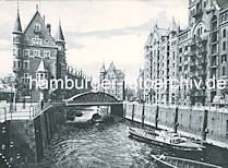 0150_18_1139 Blick �ber das St Annenfleet zur Neuerwegsbr�cke und das dahinterliegende Brooksfleet. Beladene Schuten liegen am Kai des St. Annenufer; ein Ewerf�hrer stakt mit seinem Bootshaken seinen Kahn �ber den Kanal - ein Schlepper unterquert die Br�cke und f�hrt in das Brooksfleet ein. Ein Pferdefuhrwerk transportiert S�cke auf der Strasse St. Annenufer vor dem Speicher von Hanssen & Stude. Lks. das urspr�ngliche Direktionsgeb�ude der Speicherstadtverwaltung / Hamburger Freihafen-Lagerhaus-Gesellschaft (HFLG) - in der Bildmitte hinter dem Br�ckenbogen das Speichergeb�ude G. 