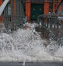 33_47909 Hochwasser in Hamburg; bei der Fischauktionshalle wird die Treppe zum Anleger Fischmarkt Altona bersplt. Die Gischt der Wellen spritzt zwischen den Holzbohlen der Wassertreppe hindurch. Im Hintergrund die Eingangstr zur Fischauktionshalle.   www.fotos-hamburg.de
