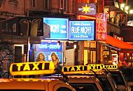 34_41205 Taxis mit beleuchteten Schildern warten am Straßenrand der Reeperbahn auf Fahrgäste;  Neonreklame lädt die Passanten zum Besuch in einer Live Show mit Table Dance ein.