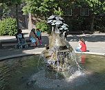 222_0457 Die Bronzeskulptur des wasserspeienden Brunnens an der Slomanstrasse auf der Veddel hat dei Knstlerin Doris Waschk-Balz 1982 entworfen. Einwohnerinnen der Veddel sitzen bei der Brunnenanlage und geniessen die Ruhe.