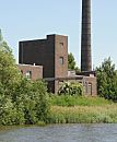 234_9505 Altes Fabrikgebude mit hohem Ziegelschornstein am Ufer des Hovekanals. Das Ufer des Veddeler Wasserwegs ist dicht mit Schilf und Struchern bewachsen.