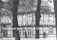 11_21487 historische Aufnahme von alten Gasthof Stadt Hamburg ca. 1936 - hohe Linden stehen an der Strasse, Passanten gehen auf dem Bürgersteig oder schieben ihr Fahrrad vor dem Fachwerkgebäude. Das ca. 1550 errichtete Gasthaus hat aufwändige Schnitzerein im Fachwerk. www.hamburger-fotoarchiv.de