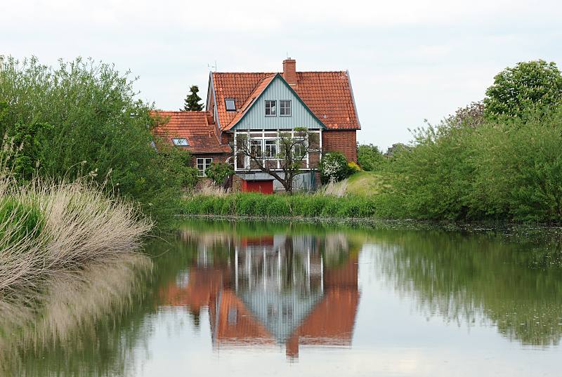 Bilder aus dem Alten Land - Lauf des Altlnder Flusses Este. Wohnhaus am Esteufer - Weiden und Schilf, Spiegelung im Wasser. 050_4296 Wohngebude direkt am Ufer der Este. Auf dem Fluss, der durchs Alte Land fhrt, herrschte zu frheren Zeiten reger Gterverkehr. Ewer mit flachem Boden und geringen Tiefgang brachten die  Obsternte der Altlnder Obstbauern auf die Hamburger Mrkte. Jetzt ist der Lauf der Este fr Sportboote ein reizvolles Wasserrevier in der Nhe Hamburgs.