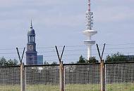 51_0099 Vom Wilhelmsburger Spreehafen kann das Panorama von Hamburg betrachtet werden. Blick durch den Zollzaun auf den Deich am Spreehafen - dahinter sind die beiden Hamburger Wahrzeichen die St. Michaeliskirche und der Heinrich Herzt Turm zu erkennen. Im Volksmund werden beide Türme auch "Michel" und "Telemichel" genannt. 