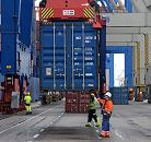 11_21405 Ein Container wird mit dem Containergreifer der Containerbrücke von der Laschplattform abgesenkt. Hafenarbeiter stehen auf dem Athabaskakai des Terminals Burchardkai und nehmen die Metallbox in Empfang.   ©www.bildarchiv-hamburg.de