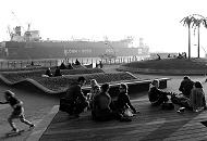14_x9831 Jugendliche sitzen im Park Fiction in der Abendsonne und entspannen sich. Auf der anderen Seite der Elbe liegt ein Tankschiff im Schwimmdock Dock 11 der Hamburger Werft Bohm  + Voss. 