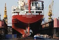 23_26-5959 Das Frachtschiff CONTAINERSHIPS V mit Heimathafen Hamburg liegt im Dock der Norderwerft am Reiherstieg. Eine Barkasse der Hamburger Hafenrundfahrt fährt an dem Heck des Containerfeeders vorbei. 