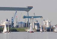 32_7444 Die Elbe bei Neuenfelde - an der Klappbrücke und dem Este- Sperrwerk (re.) legt gerade die Fähre nach Hamburg Blankenese zum gegenüberliegenden Elbufer ab - Jollen segeln auf der Elbe. Hinter dem Elbdeich liegt die Sietas Werft mit der gewaltigen Krananlage und kleineren Rollkränen; lks. liegt ein Frachtschiff im Dock, während re. die Aufbauten eines Schiffs zu erkennen ist, das am Este-Ufer der Werft im Werfthafen liegt.
