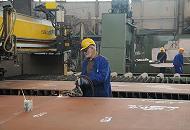 41_5083 Schweissarbeiten auf der Sietas-Werft in Hamburg Neuenfelde. Im Hintergrund transportieren zwei Werftarbeiter ein zugeschnittenes Stahlblech mit einem Kran.  ©www.fotos-hamburg.de