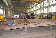 42_5095 Zwei Werftarbeiter der Sietas-Werft flexen in der Werkhalle die Kanten eines zugeschnittenen Stahlblechs - im Hintergrund stehen schon fertige Schiffssegmente.