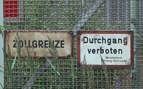 011_17366 - Hinweisschilder am Maschendrahtzaun: Zollgrenze, Durchgang verboten, Hauptzollamt Hamburg Kehrwieder. Wildkraut wchst am Zaun und beginnt die alten Schilder zu bedecken. 