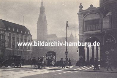 011_15661 - Aufnahme von ca. 1920 ber den Jungfernstieg zu den Arkaden und dem Rathaus; ein Kraftfahrzeug steht am Strassenrand, ein Mann transportiert Zeitungen mit seinem Fahrrad; auf der Reesendammbrcke befindet sich ein Zeitungskiosk.