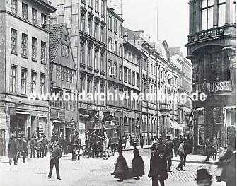 04_22731 Blick in den Neuen Wall ca. 1920; Passanten überqueren die Strasse, eine Pferdekutsche wartet auf ihre Fahrgäste - die Herren tragen Melone und Spazierstock.