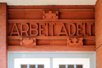 0005 ARBEIT ADELT - Inschrift über dem Eingang eines Wohnhauses in Hamburg Barmbek Süd.
