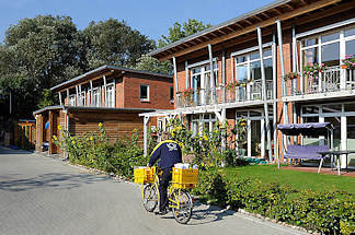 9165 Neubausiedlung / Passivhäuser im Zassenhausweg - ein Briefträger fährt mit seinem Postfahrrad die Zustelltour.