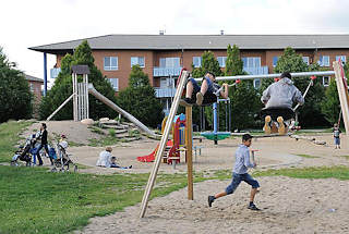 5040 Kinderspielplatz Neuallermöhe - Jungendliche auf einer Schaukel -  Mütter spielen mit ihren Kindern im Sand.