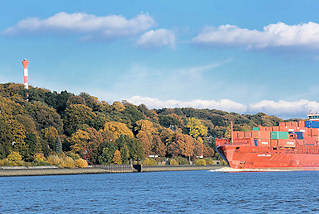 6172 Der Containerfeeder LAURA ANN auf der Elbe vor Hamburg Nienstedten - am Elbhang Herbstbäume bis herunter zum Elbufer. Rotes Frachtschiff mit Containerfracht, blauer Himmel weisse Wolken.