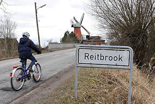 0592 Stadtteilschild Reitbrook - Fahrrad auf der Strasse - Mühle von Hambug Reitbrook im Hintergrund.