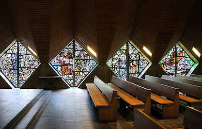 2457 Sitzbänke und leuchtende Glasmosaikfenster der Saseler Lukaskirche.