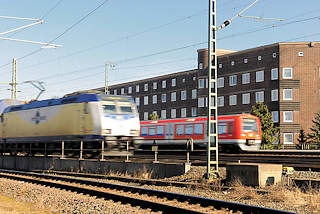 2920 Fahrender Metronomzug und  S - Bahn auf den Gleisen auf der Veddel - Bahnstrecke am Wohngebiet; Klinkerhäuser auf der Hamburger Veddel.