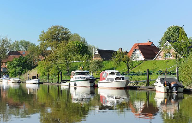 Ausflugsziel bei Hamburg - Obstblte im Alten Land - der Fluss Lhe bei Grnendeich. Sportboote liegen am Anleger - Huser hinter der Deichkrone. 015_3989 Bootsanleger an der Lhe - Sportboote liegen in der Frhlingssonne am Ponton. Hinter dem Deich sind die Dcher der Huser zu sehen, die an der dahinter liegenden Deichstrasse stehen.