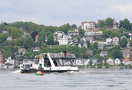 028_7375 Die Elbfhre ALTONA kommt vom Anleger Cranz und berquert die Elbe Richtung Hamburg Blankenese. Am gegenber liegenden Elbufer der Strand von Blankenese und die Huser am Sllberg. Im Vordergrund ein Schifffahrtszeichen, dass das Fahrwasser der Fhrverbindung markiert. Eine  Fahrwasserkenn- zeichnung ist auch notwendig, da groe Teile des Mhlenberger Lochs bei Ebbe trocken fllt. Die Grn-rote Tonne weist auf das abzweigende Fahrwasser zur Este hin.