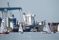 029_4164 Eine Regatte von Optimisten-Jollen findet auf der Elbe beim Mhlenberger Loch statt - eine Elbfhre der HADAG legt gerade vom Anleger Cranz ab. Hinter der Klappbrcke die ber die Mndung der Este und dessen Sperrwerk fhrt ist ein Kran und Schiffsaufbauten der Neuenfelder Sietas-Werft zu erkennen.