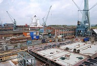 032_5191 Blick ber die Sietas-Werft in Hamburg Neuenfelde. Im Vordergrund liegt ein halbfertiges Schiffssegment, whrend hinter den Arbeitshallen die frisch gestrichenen Aufbauten ein Schiffsneubaus zu erkennen sind. Die traditionsreiche Sietas Schiffswerft hat ihren Ursprung schon 1635 - an der Este gab es frher viele Schiffswerften, auf denen u.a die Lastsegler fr den Gtertransport gebaut wurden.