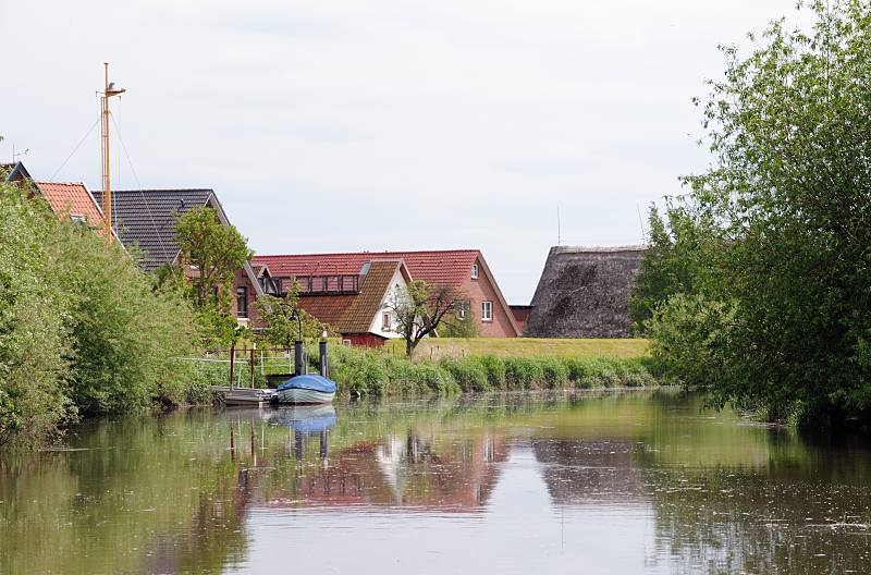 Bilder aus dem Alten Land, Wohnhuser hinter dem Deich - Sportboot am Anleger.  049_7463 Die Wohnhuser stehen vor Hochwasser geschtzt hinter dem Deich der Este. Auf dem Fluss herrschte zu frheren Zeiten ein reger Gterverkehr, der mit Lastseglern ausgefhrt wurde. Diese brachten die Waren an ihre Zielorte, wie z. B. die Obsternte auf die Hamburger Mrkte. Jetzt ist der Lauf der Este ein reizvolles Sportbootrevier -  die Fahrt entlang Obstbumen und kleinen Ortschaften. Wo frher die Berufsschiffer ihre Khne ankerten, befinden sich heute entlang des gesamten Verlaufs von Buxtehude bis Cranz zahlreiche Schlengel/ Liegepltze fr Segel- und Motorboote.