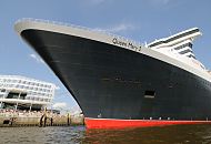 02_4353 Bug der Queen Mary 2 am Kreuzfahrtterminal im Hamburger Hafen. Schaulustige Hamburger stehen auf einer  Terrasse der Hafencity und bewundern das riesige Schiff. Die R.M.S. (Royal Mail Ship)  Queen Mary 2 (QM2) ist mit 148.528 BRZ eines der größten Passagierschiff der Welt. Das britische Kreuzfahrtschiff  hat eine Länge von 345 m und eine Breite von 45 m. Der Luxusliner bietet in 1310 Kabinen bis zu 2.620 Passagieren Platz und hat eine Besatzung von 1.253 Personen. Die Queen Mary 2 hat fünf Swimmingpools, einen Ballsaal, Golfanlage, Wintergarten, Sportzentrum, mit über 8.000 Büchern die größte Bibliothek auf See, den größten öffentlichen Saal (Restaurant Britannia), der über zwei Decks und die gesamte Schiffsbreite geht, acht weitere Restaurants, Fitness-Center, Planetarium, Kino, Theater.  ©www.fotograf-hamburg.de