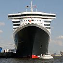03_4359 Das Kreuzfahrtschiff Queen Mary 2 liegt festgetäut am Kai des Cruise Centers im Hamburger Hafen. Passagiere einer weissen Motoryacht sitzen an Deck und betrachten das grosse Schiff von der Nähe. Die R.M.S. (Royal Mail Ship)  Queen Mary 2 (QM2) ist mit 148.528 BRZ eines der größten Passagierschiff der Welt. Das britische Kreuzfahrtschiff  hat eine Länge von 345 m und eine Breite von 45 m. Der Luxusliner bietet in 1310 Kabinen bis zu 2.620 Passagieren Platz und hat eine Besatzung von 1.253 Personen. ©www.fotograf-hamburg.de