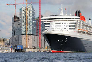 8552 Das Kreuzfahrtschiff Queen Mary läuft aus dem Hamburger Hafen aus - im Hintergrund die Baustelle der Elbphilharmonie mit hohen Baukränen. Ausflugsschiffe mit Touristen an Bord begleiten das Passagierschiff beim Auslaufen aus dem Hamburger Hafen.