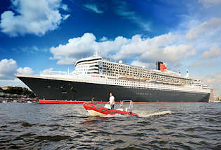 8582 Die 345m lange Queen Mary 2 verlässt Hamburg und fährt Höhe Landungsbrücken - ein rotes Schlauchboot, Motorboot begleitet das Kreuzfahrtschiff auf der Elbe im Hamburger Hafen. 
