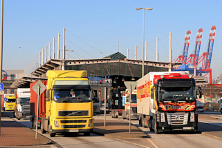0288 LKW haben die Zollgrenze und Zollstation des Hauptzollamt Waltershof durchfahren - im Hintergrund hochgefahrene Containerbrücken des Containerterminals Waltershof.
