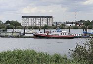 11_17526 Blick ber den Holzhafen in Hamburg Moorfleet - auf der gegenber liegendes Seite der Moorfleeter Deich und die typische Industriearchitektur eines Lagergebudes. An den Bootsstegen des ehemaligen Laufs der alten Doveelbe sind Boote vertut.